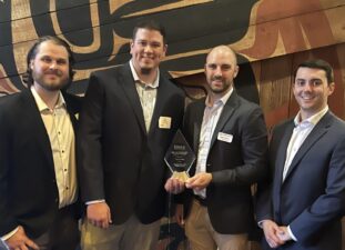 Four individuals holding an award.