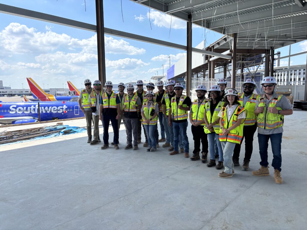 Group stands in construction gear in front of Southwest airplane.