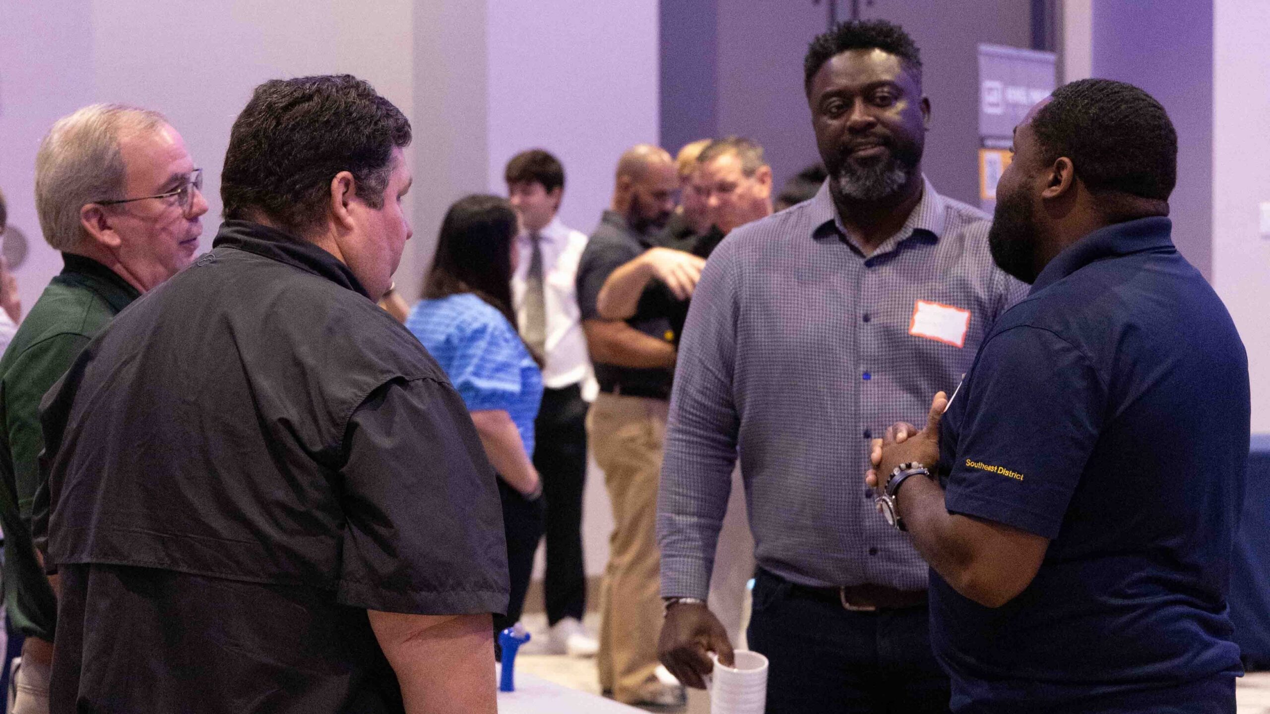 Attendees gather around a booth during the event, engaging in conversation.