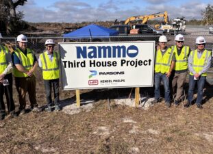 Construction team stands next to NAMMO Third House Project at build site