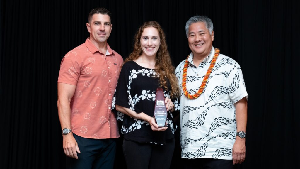 Two Hensel Phelps representatives pose with the Build Hawaii Award of Excellence for the Aircraft Maintenance Hangar project.