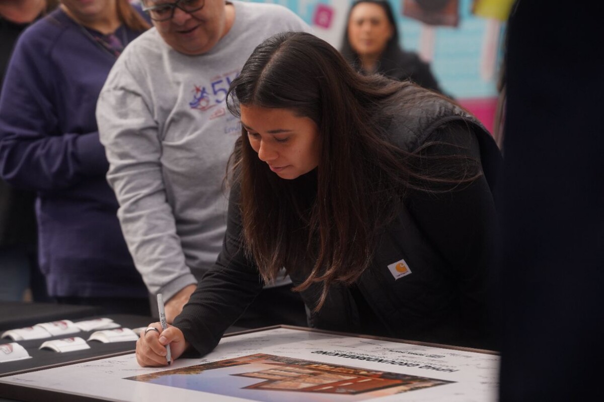 Hensel Phelps corporate office employees sign a commemorative photo of project rendering.